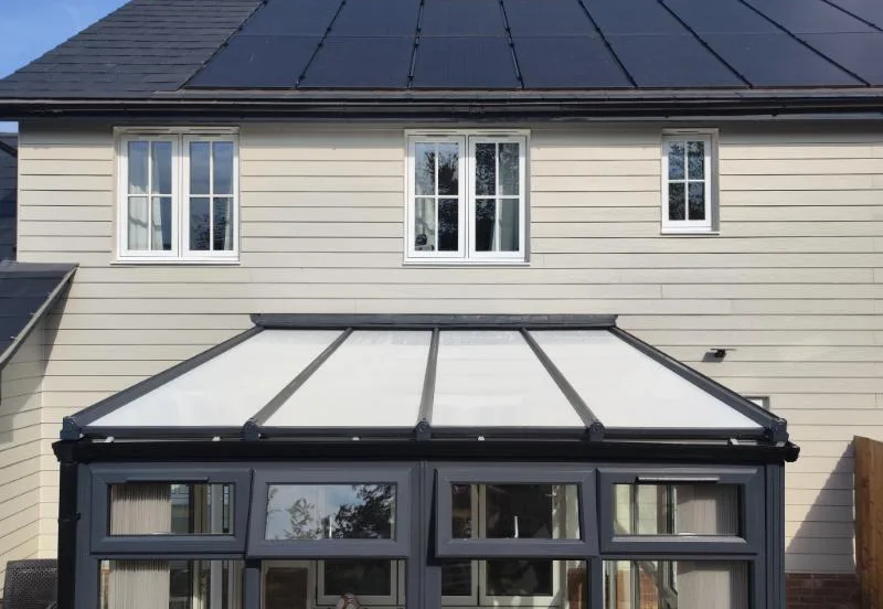 The same conservatory from the same spot with an insulated panel roof in place of the old glazing, white composite panels between dark grey bars.